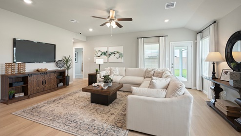 Pleasant Hill Model Home living room with large sectional and tv console with access to backyard.