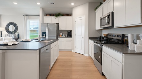 Pleasant Hill Model Home open-concept kitchen with island, stainless-steel appliances, and vinyl plank flooring.
