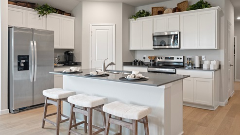 Pleasant Hill Model Home open-concept kitchen with gray quartz countertops and white cabinetry.