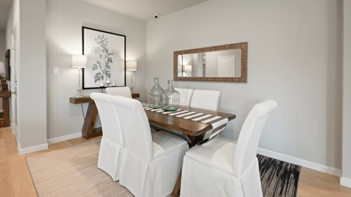 Pleasant Hill Model Home dining area with dining table and white parson chairs.