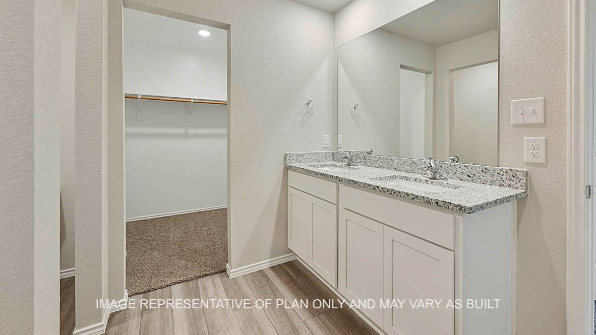 Bellvue primary bathroom with white cabinets, granite countertops, vinyl plank flooring, and view to closet.