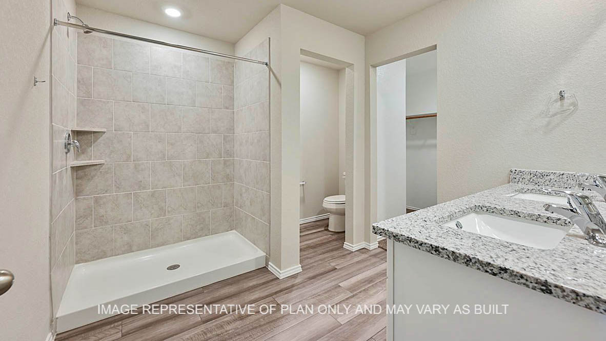 Bellvue primary bathroom with white cabinets, granite countertops, vinyl plank flooring, and ceramic tile surround shower.
