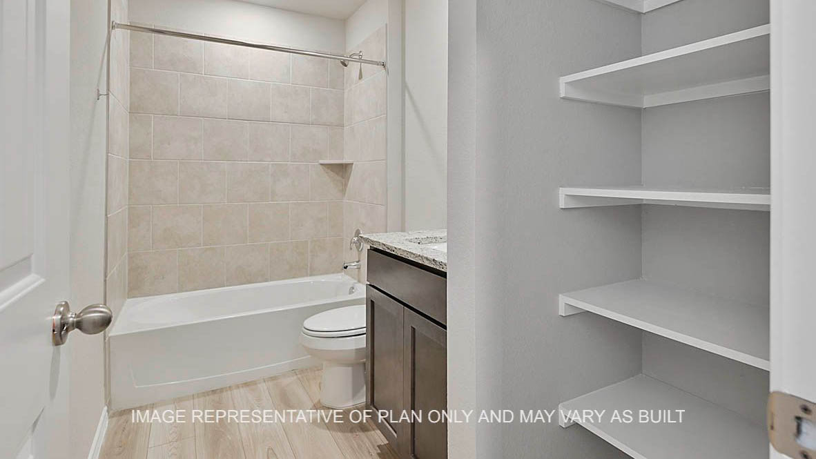Fargo secondary bathroom with dark stained cabinetry, granite countertops, linen shelving, ceramic tile shower bath surround and vinyl plank flooring.