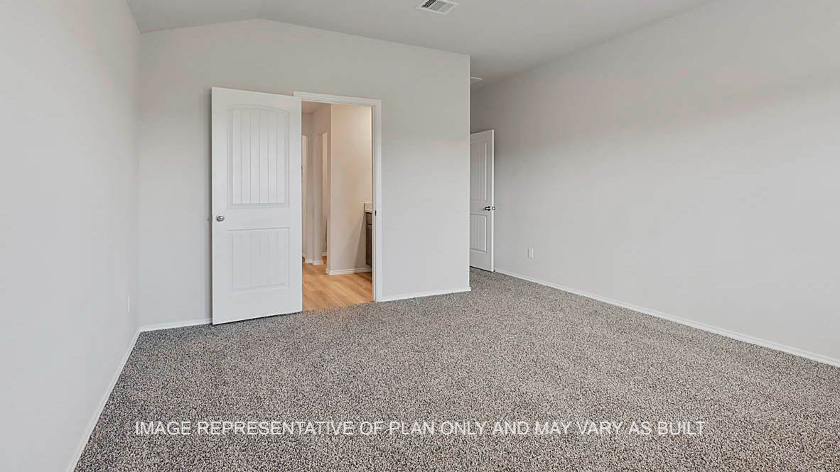 Fargo primary bedroom with carpeted flooring and view to bathroom.