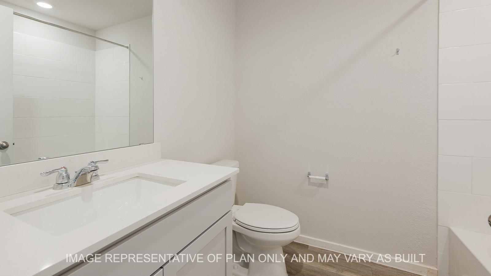 Midland secondary bathroom with grey cabinetry, granite countertops, ceramic tile shower tub surround, and vinyl plank flooring.