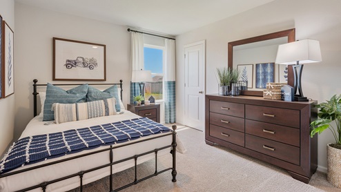 Liberty Village secondary bedroom with window, bed, dresser, and carpeted flooring.
