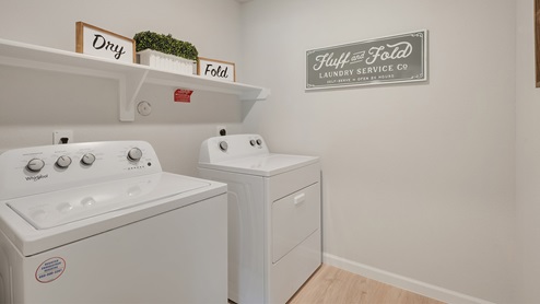 Liberty Village utility room with washer, dryer, and overhead shelf.