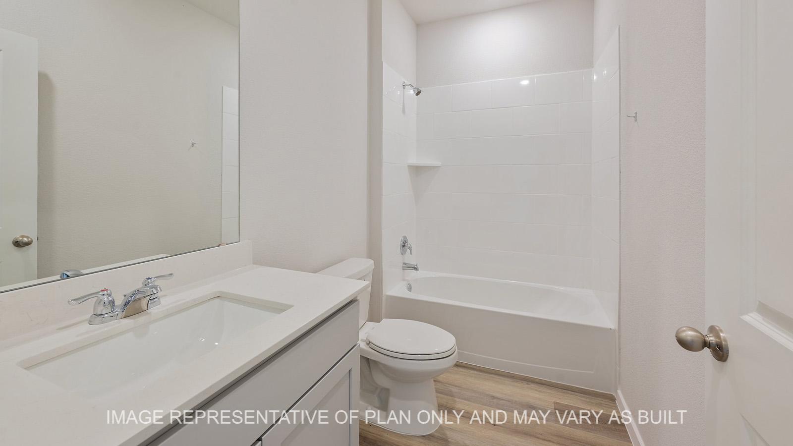 Midland secondary bathroom with grey cabinetry, granite countertops, ceramic tile shower tub surround, and vinyl plank flooring.