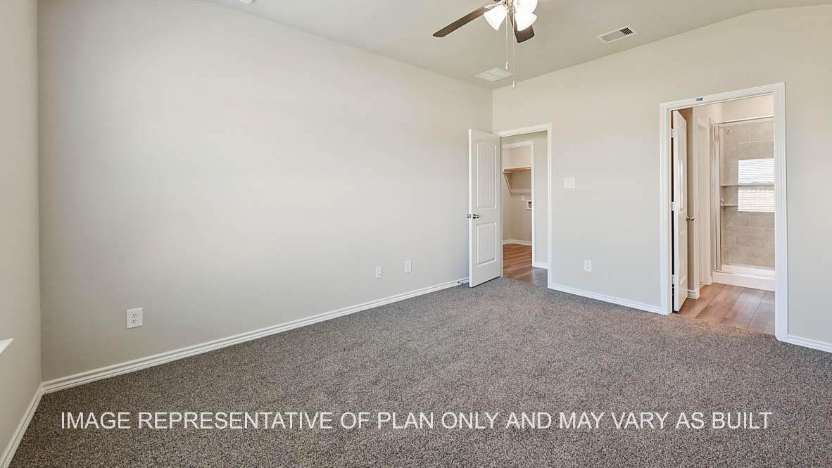 Auburn primary bedroom with carpet flooring and view into primary bath.