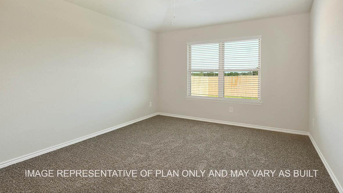 Auburn primary bedroom with carpet flooring and windows with view into backyard.