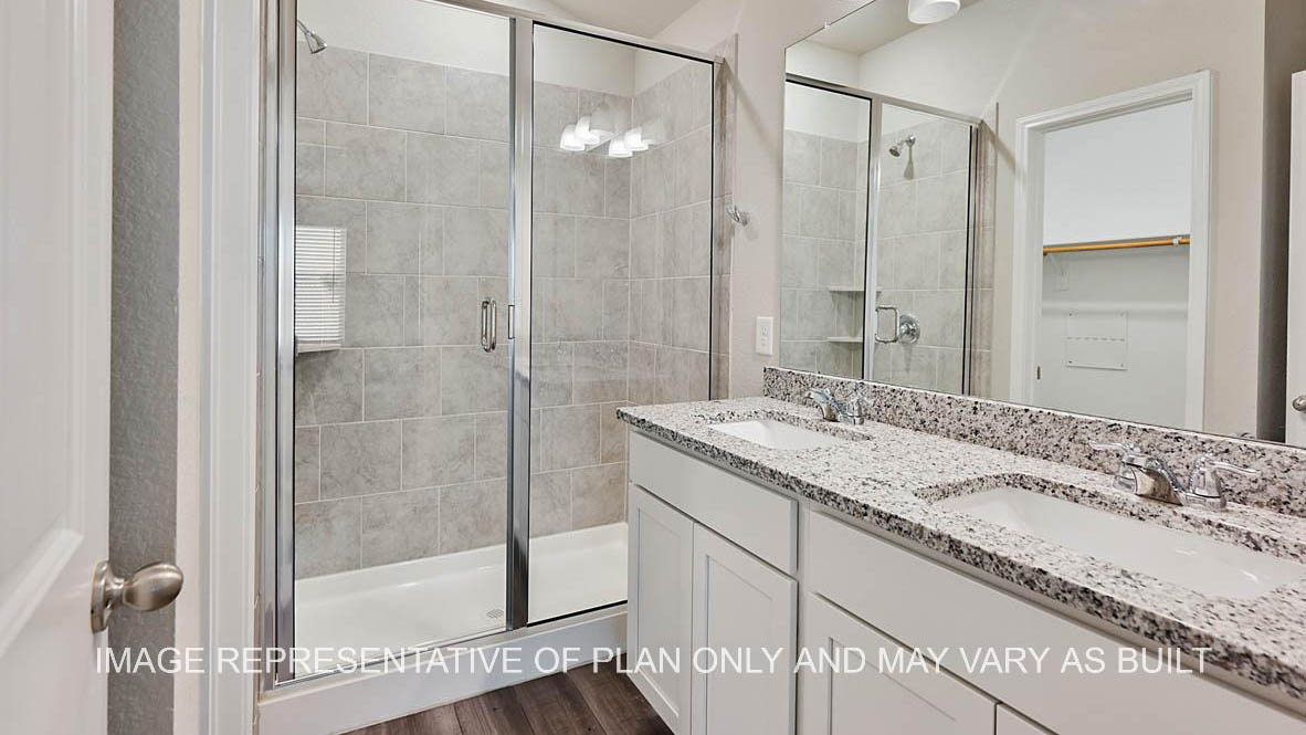 Auburn primary bathroom with white cabinets, granite dual vanity countertops, ceramic tile shower surround and vinyl plank flooring.