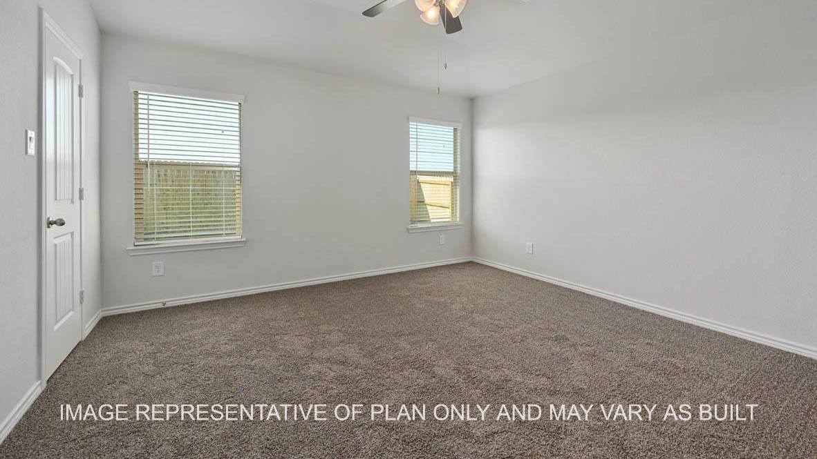 Roosevelt primary bedroom with carpet flooring and two windows.