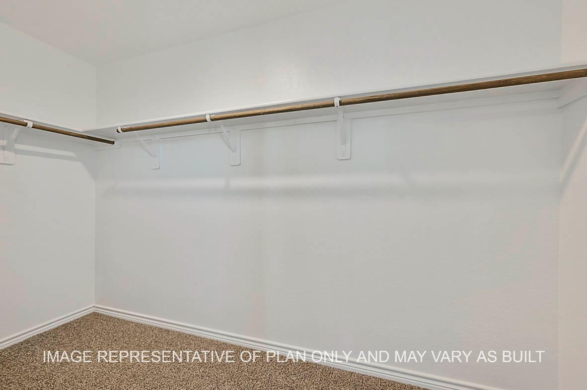 Roosevelt primary bedroom closet with carpet flooring.