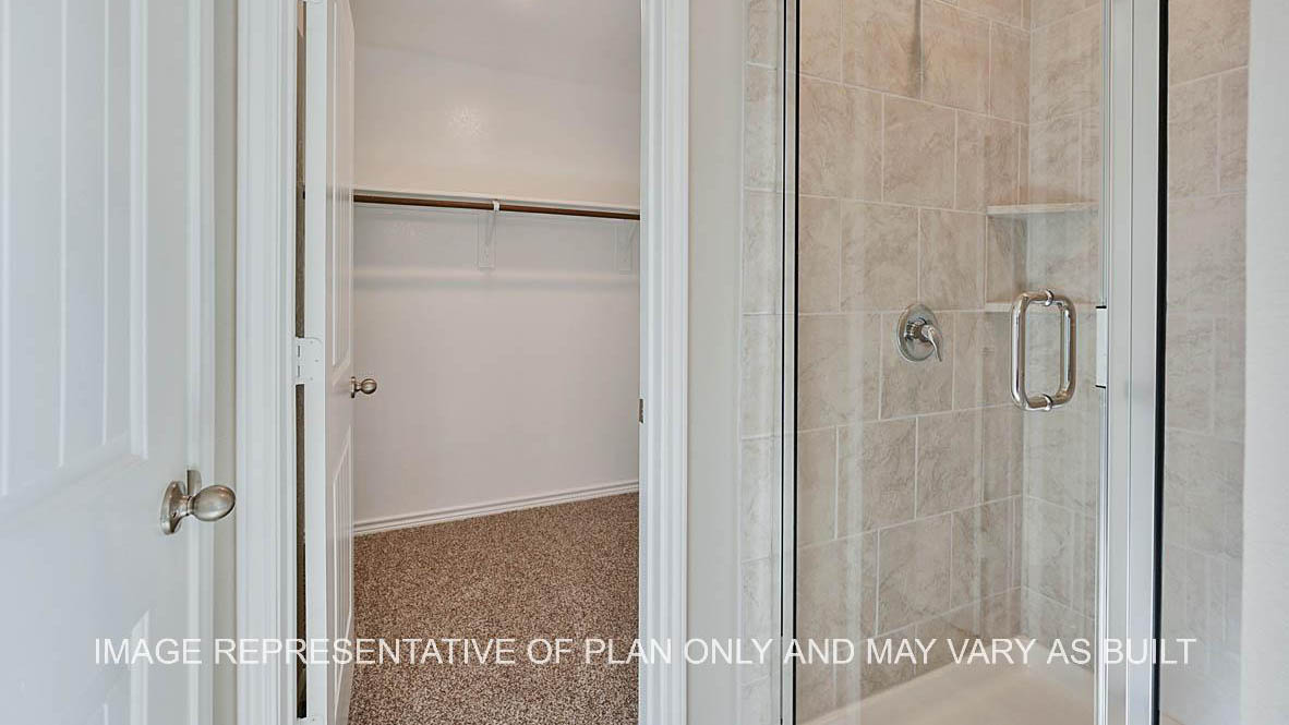 Richmond primary bathroom with ceramic tile shower surround and view to closet.