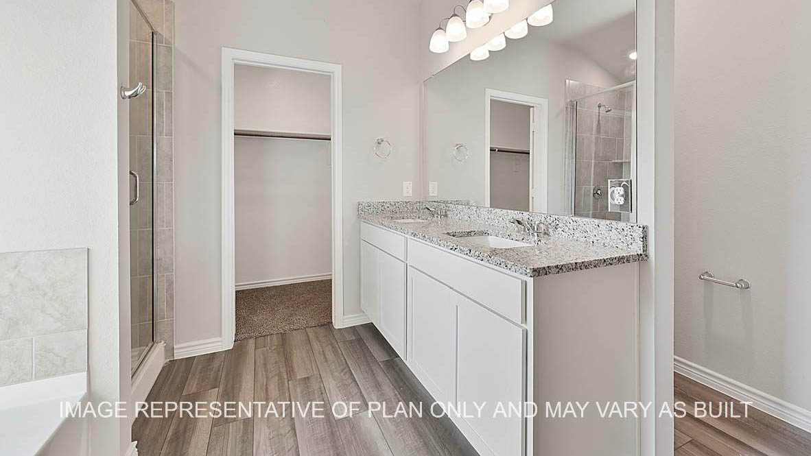 Prescott primary bathroom with vinyl plank flooring, separate tub and shower with ceramic tile surround, white cabinets and granite countertops.