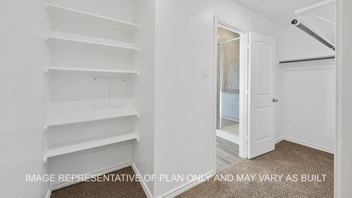 Prescott primary walk-in closet with carpet flooring and view to bathroom.