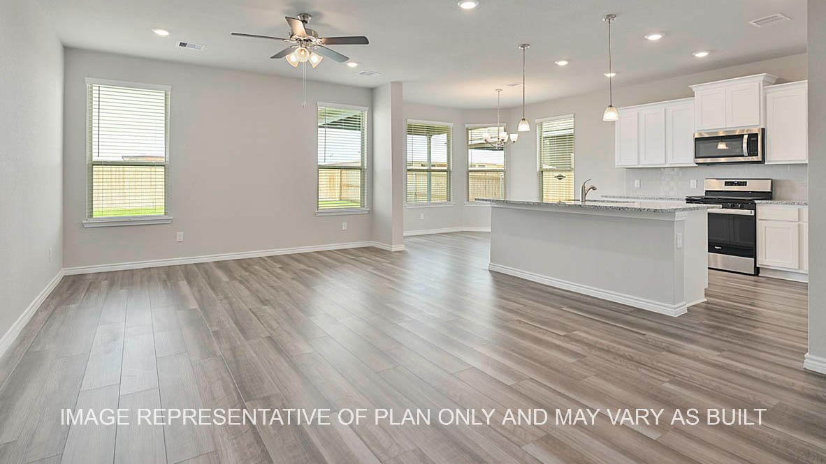 Sonoma living room with large windows and vinyl plank flooring, open to the kitchen.