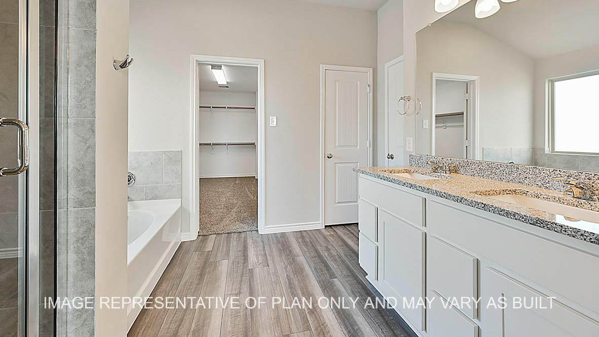 Kiawa primary bathroom with granite countertops, white cabinets, ceramic tile shower and tub surround, laminate flooring, and view to closet.