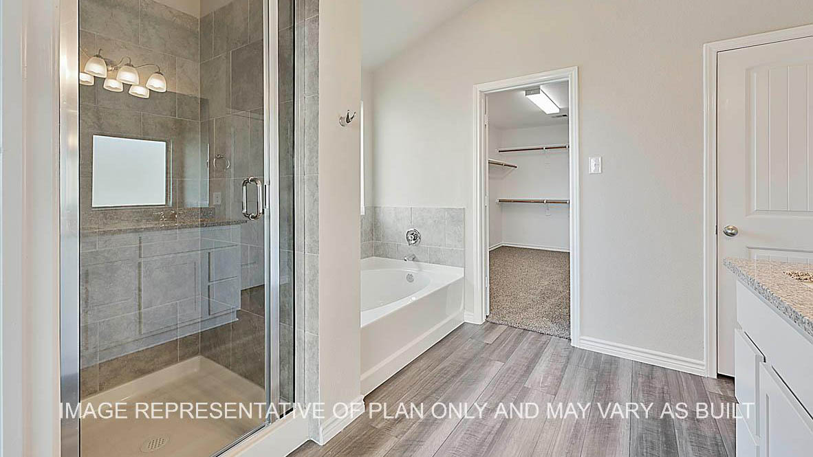 Kiawa primary bathroom with granite countertops, white cabinets, ceramic tile shower and tub surround, laminate flooring, and view to closet.