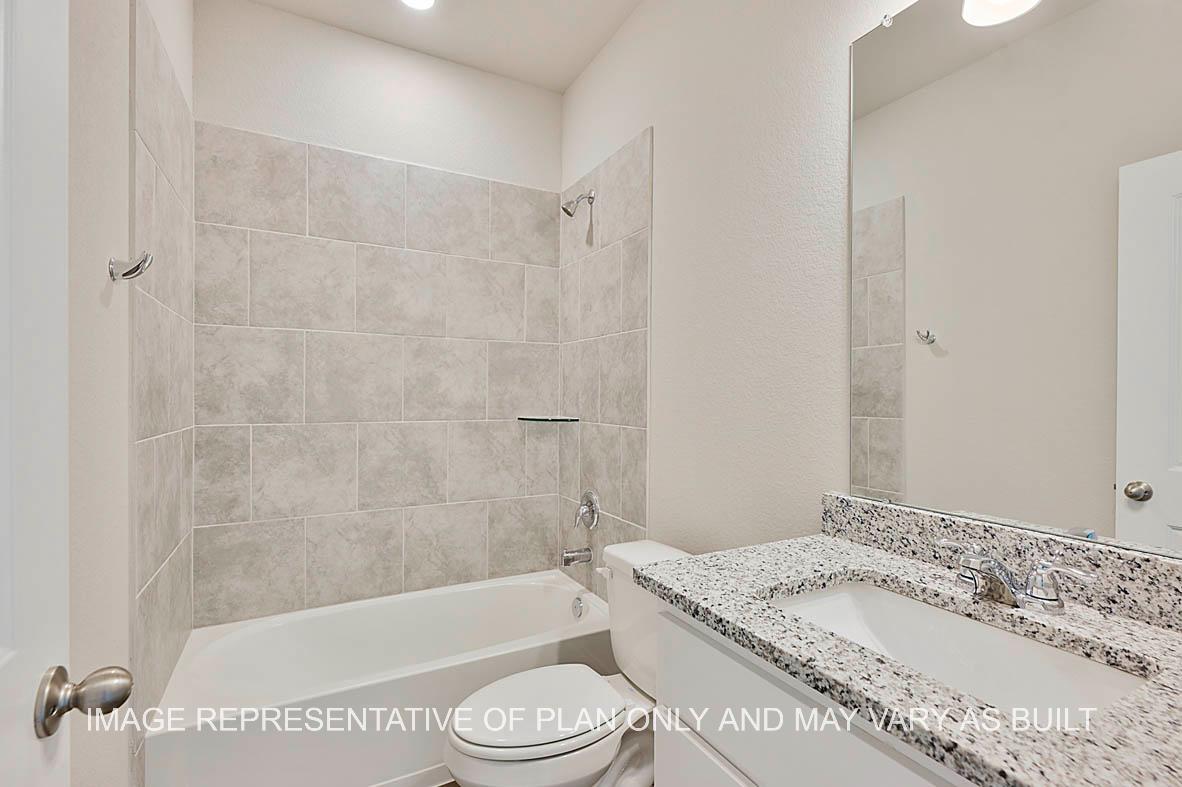 Kiawa secondary bathroom with granite countertops, white cabinetry, ceramic tile surround, and vinyl plank flooring.
