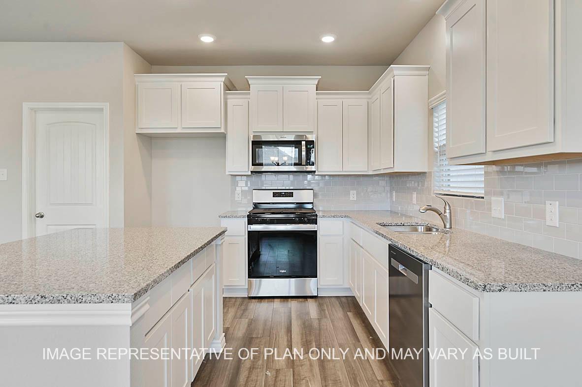 Kiawa kitchen with white cabinetry, granite countertops, tile backsplash, vinyl plank flooring and kitchen island.