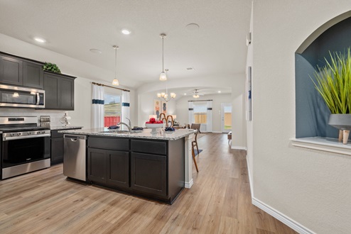 Southern Pointe model home with dark cabinetry, kitchen island, granite countertops, and view to open-concept living room