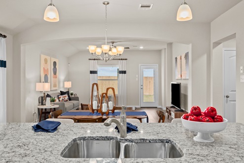 Southern Pointe model home granite kitchen island with sink and view to open-concept living