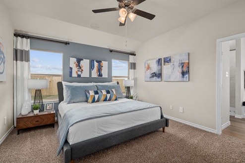 Southern Pointe model home primary bedroom with windows, carpeted flooring, and ceiling fan