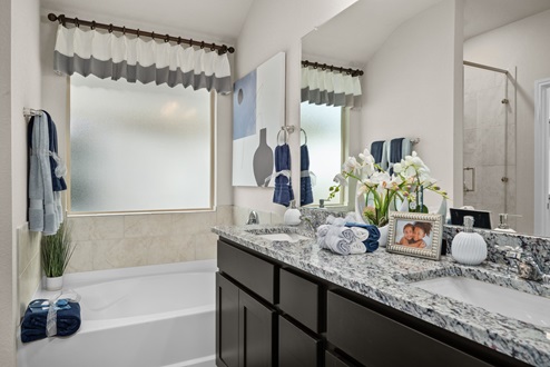 Southern Pointe model home primary bathroom with tub, granite countertops, and shaker cabinets
