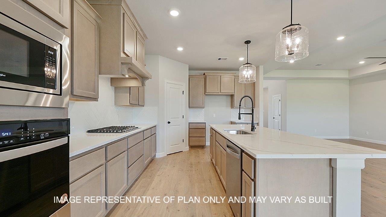 Brighton kitchen with light stained cabinets, white backsplash, quartz countertops and laminate wood flooring.