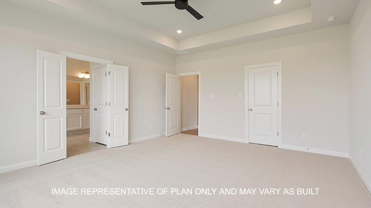 Oxford primary bedroom with carpet, view to primary bath 1 and matte black ceiling fan.
