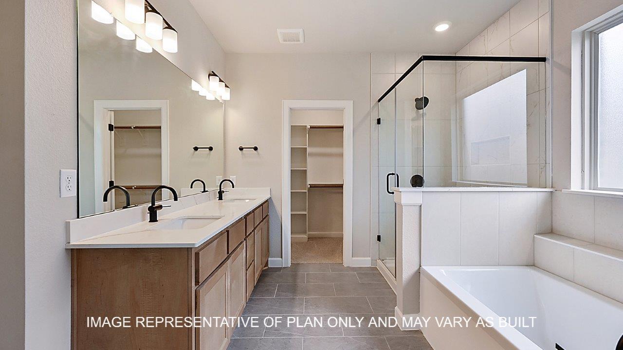 Stratford primary bathroom with tile flooring, separate tub and shower, light stained cabinets and white quartz countertops.