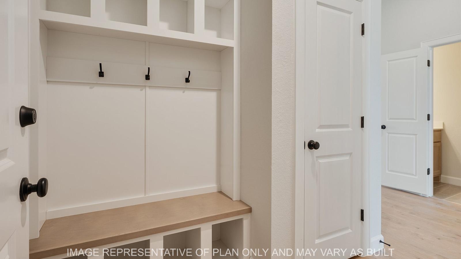 Weston mudroom with four cubbies and hooks, next to a storage closet.