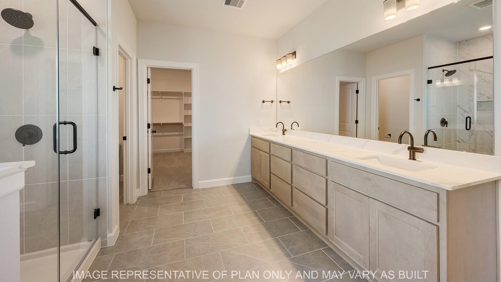 Weston primary bathroom with dual quartz vanity, blonde maple cabinetry, and tile flooring.