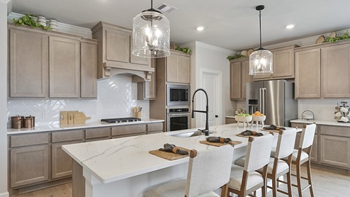 Large kitchen island and light stained cabinets.