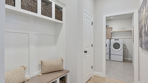 Mud room with white cabinets for storage.