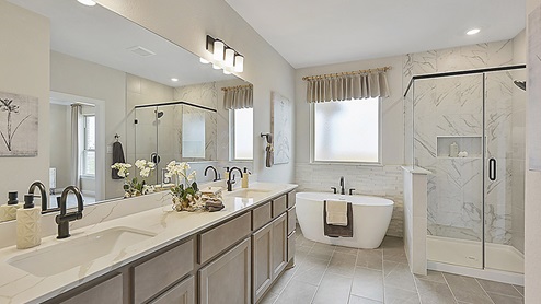Beautiful primary bathroom with dual vanities and separate free-standing tub and shower.