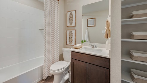 Cornerstone Caroline secondary bathroom with quarts vanity, shower/tub combo, and linen shelving.