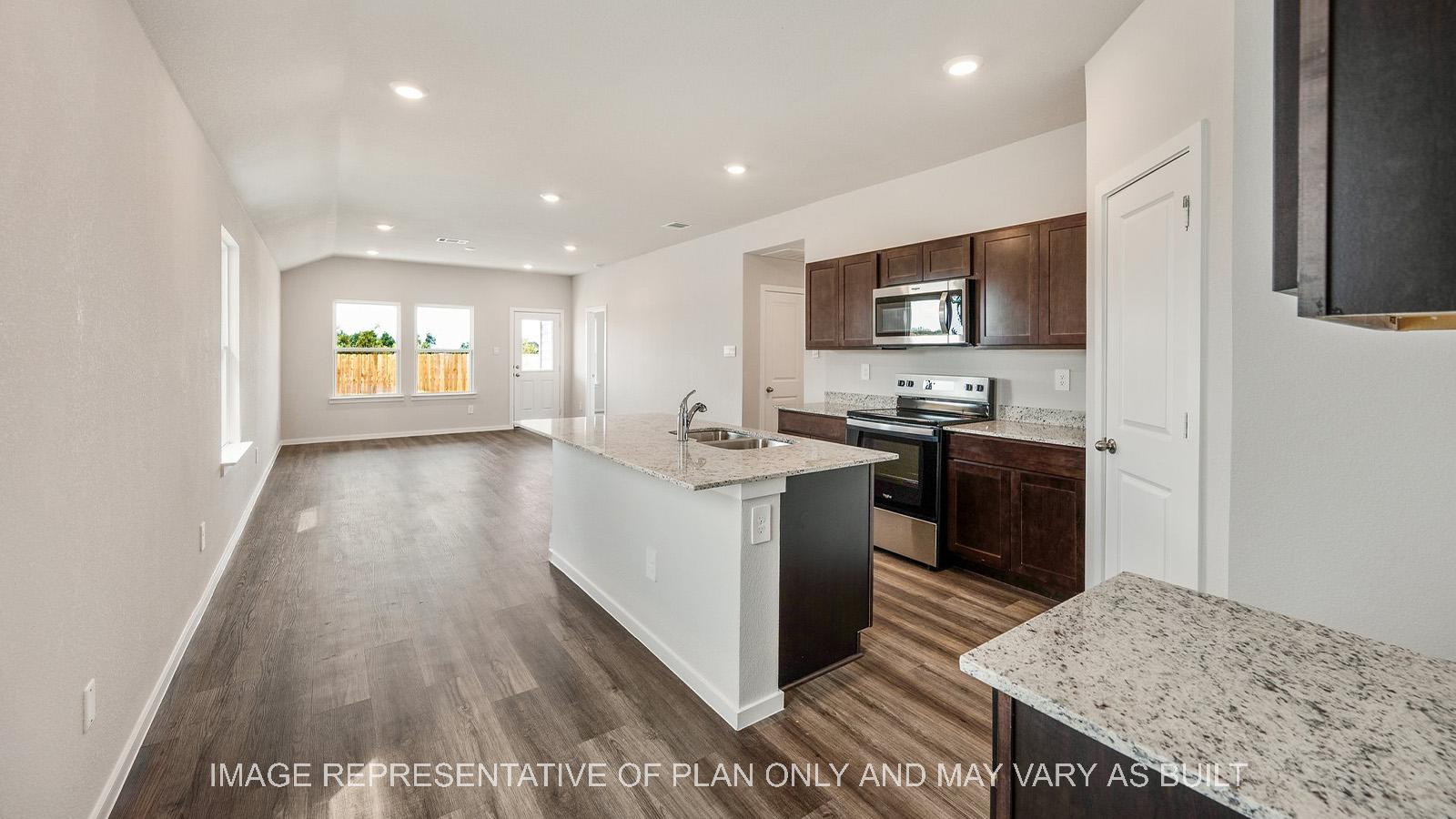 Amber kitchen with dark stained cabinetry, granite countertops, and vinyl plank flooring.