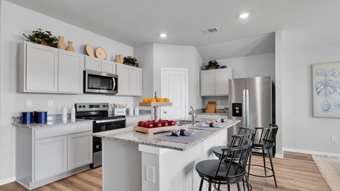 Cornerstone furnished Kitchen with white cabinetry and vinyl plank flooring.