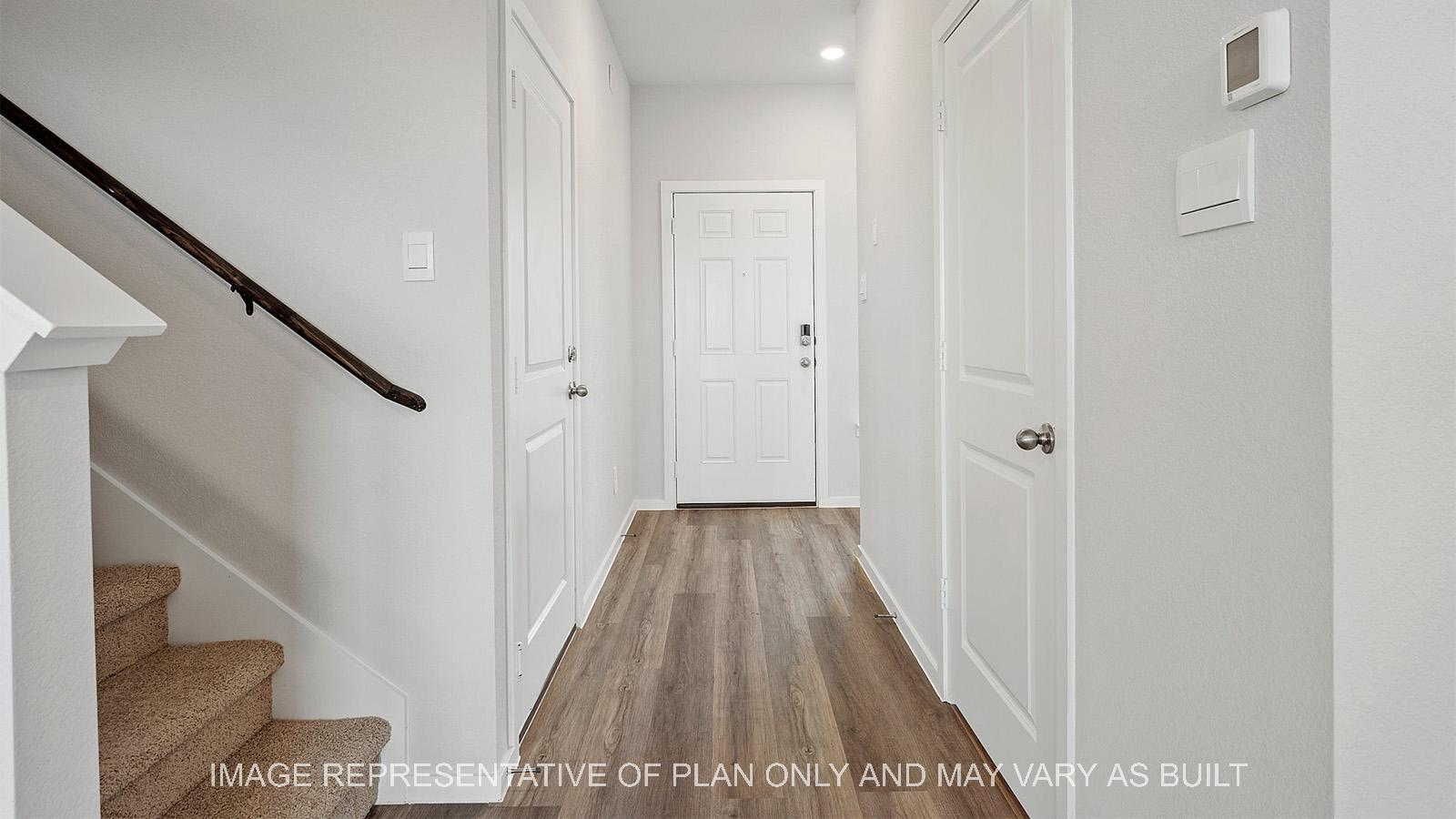 Emma entryway with carpeted staircase, garage access, and powder bath.