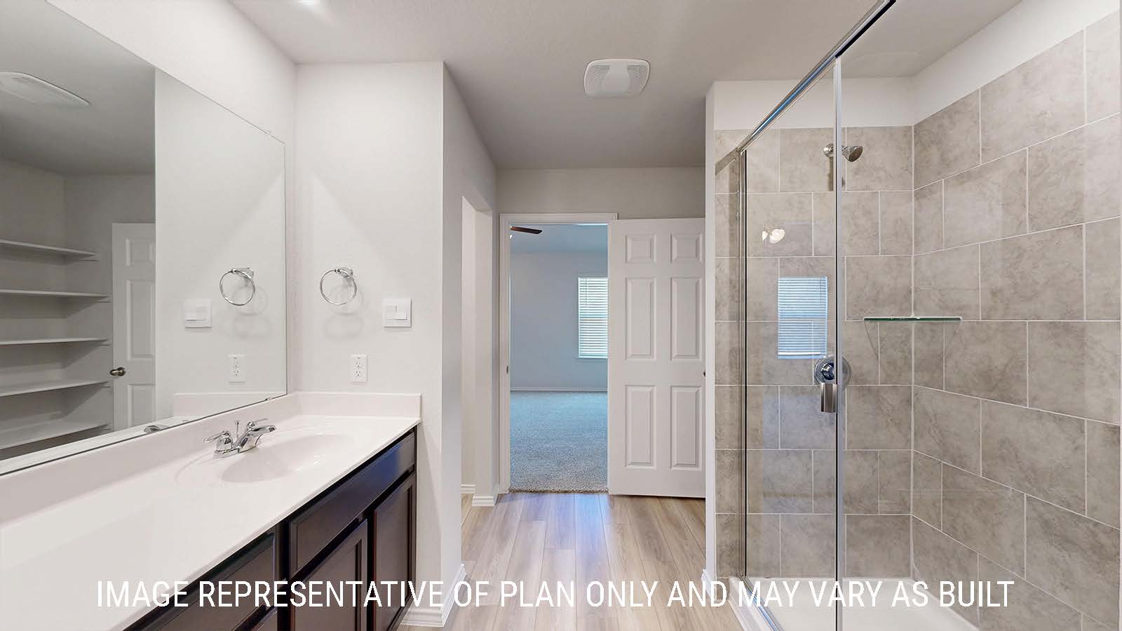Caden primary bathroom with vanity sink and walk-in shower with view of primary bedroom.