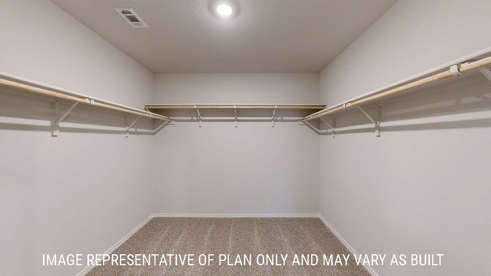 Caden primary closet with carpeted flooring and shelving for storage.