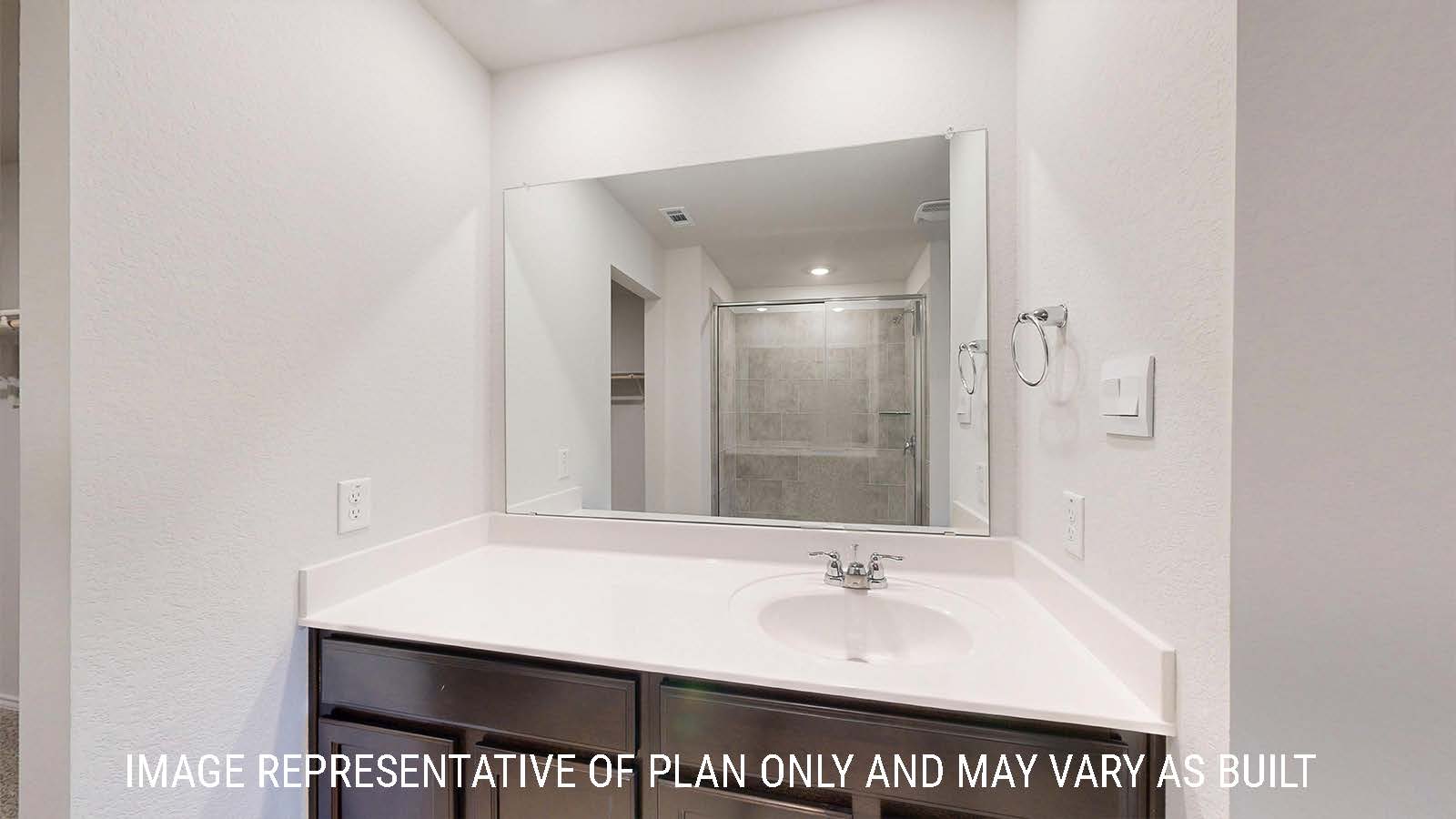 Caden primary bathroom with vanity sink and dark cabinets and walk-in shower.