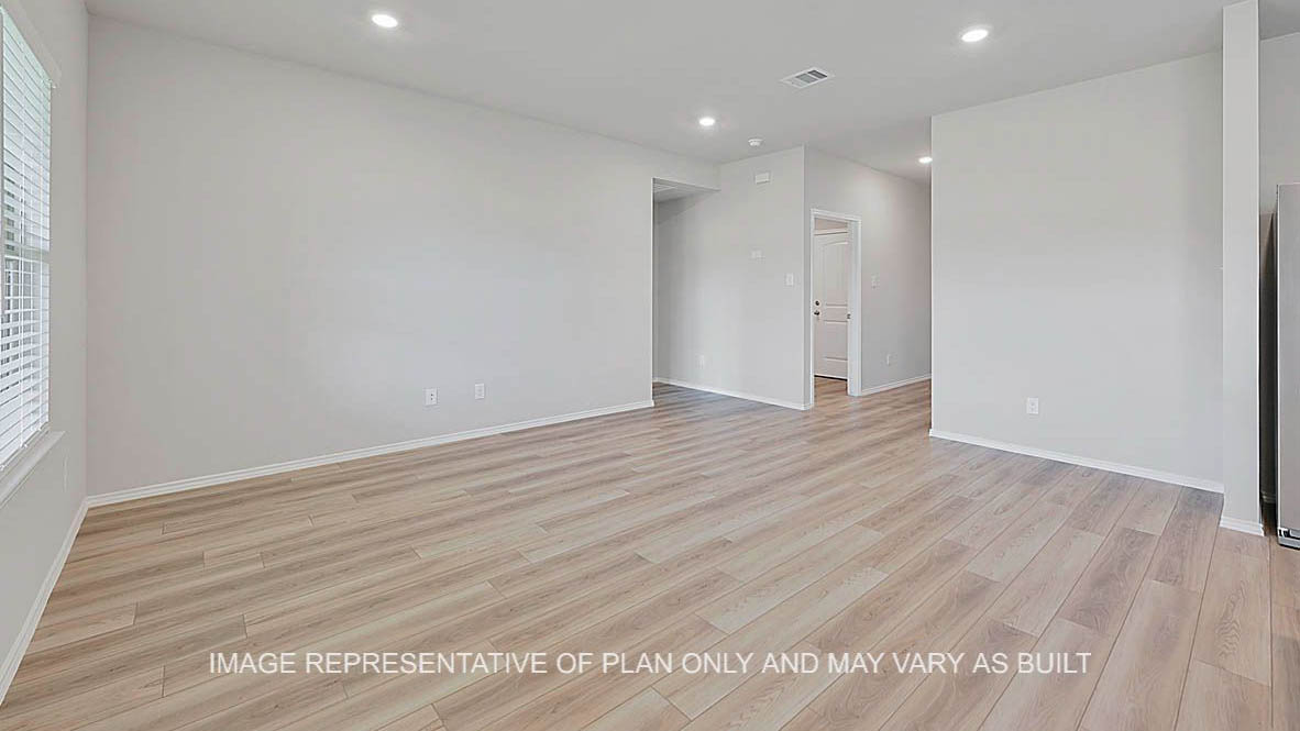 Fargo open-concept living room with vinyl plank flooring and view to primary bedroom and entryway.