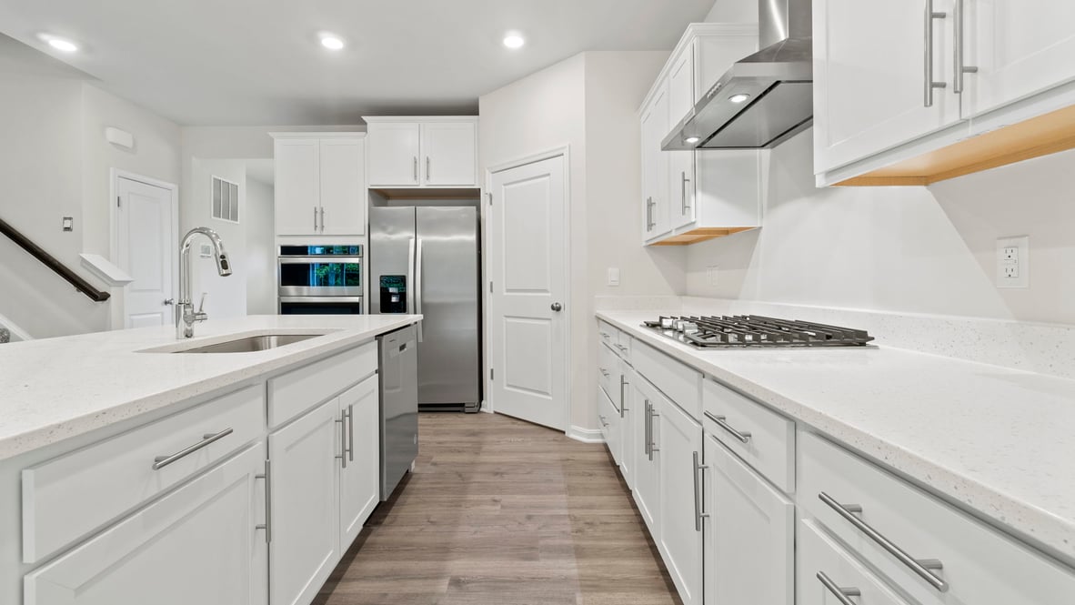 The kitchen features white cabinets and stainless steel appliances