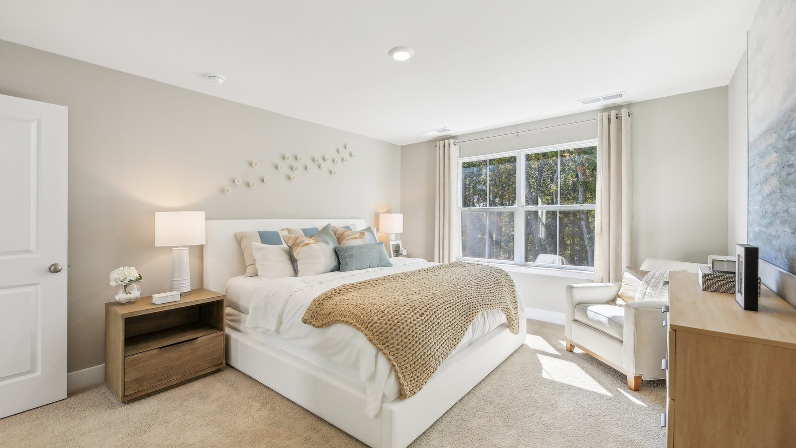 Our spacious primary bedroom is decorated with 2 night stands, an armchair, and a dresser