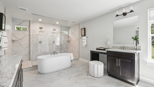 luxurious primary bathroom with floor to ceiling shower and a tub