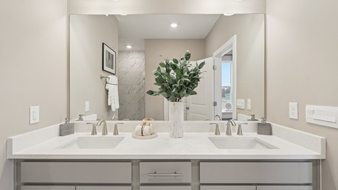 Beautiful dual vanity in the primary bathroom as well as a large mirror