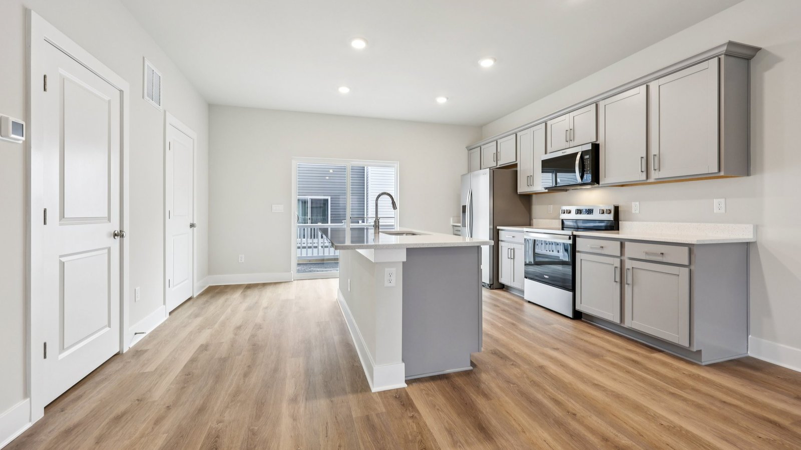 Kitchen and dining — white cabinetry, round table, and island beside window and sliding doors.